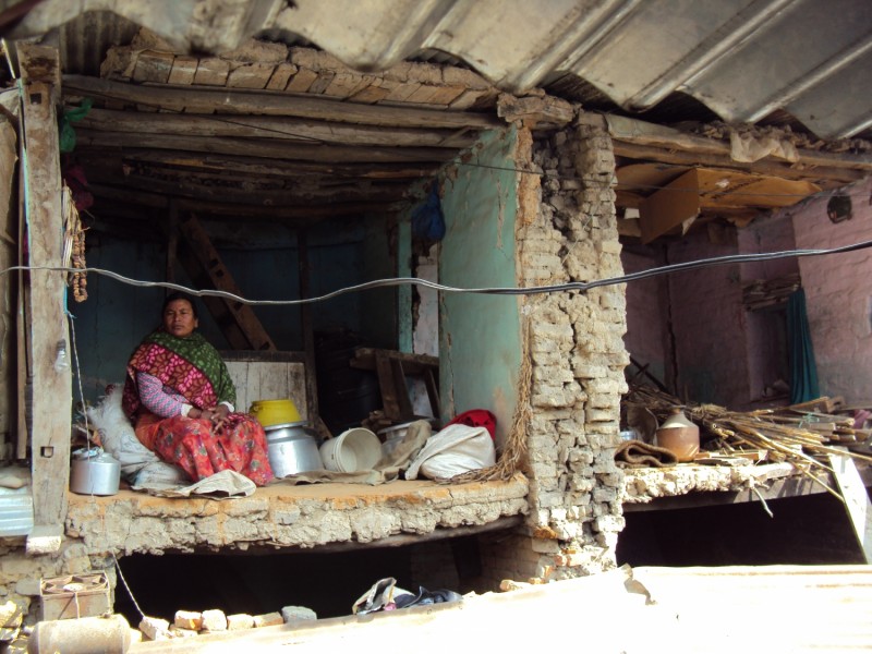Nepáli asszony a földrengés által elpusztított otthona romjai között Khokanában. A külföldi és állami segélyek ellenére legalább 7 év, mire családja új otthont építhet magának. Addig is gyermekeivel és unokáival választhatnak, hogy a fóliával fedett átmeneti szálláson vagy a romok között éljenek.